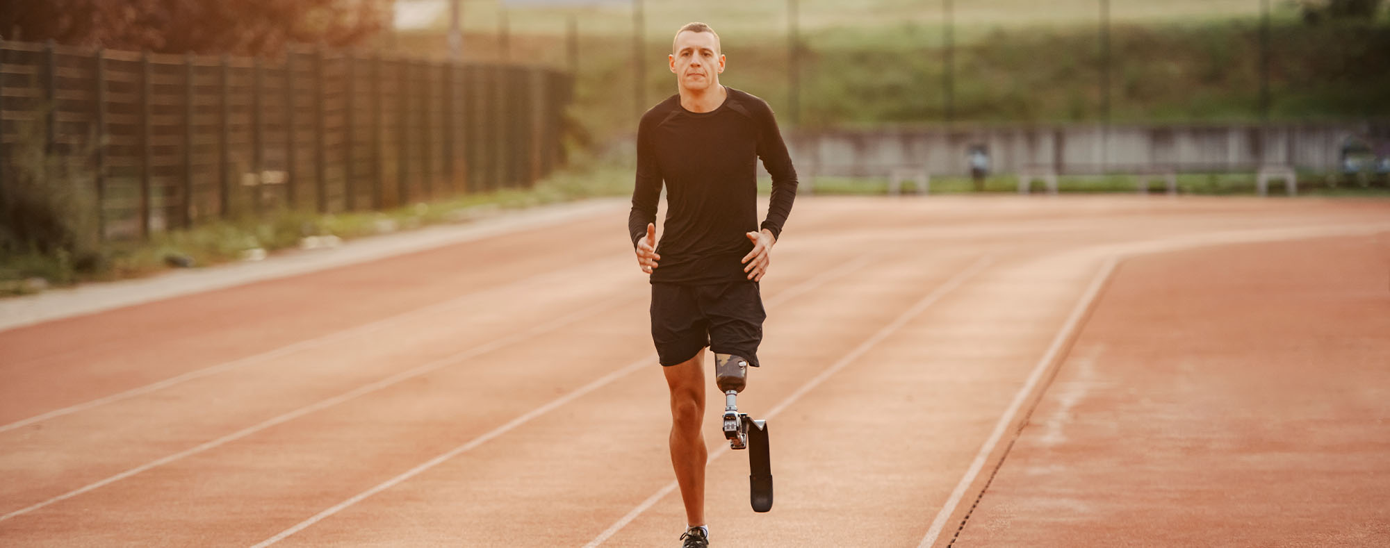 A male running on a track with a prosthetic leg.