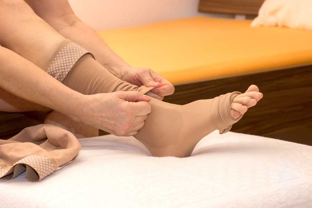 A person placing compression socks on their feet.