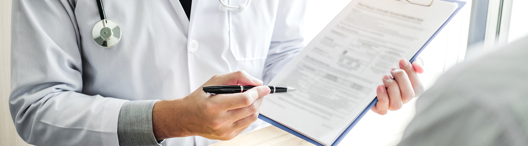 Doctor discussing information on a clipboard with their patient.